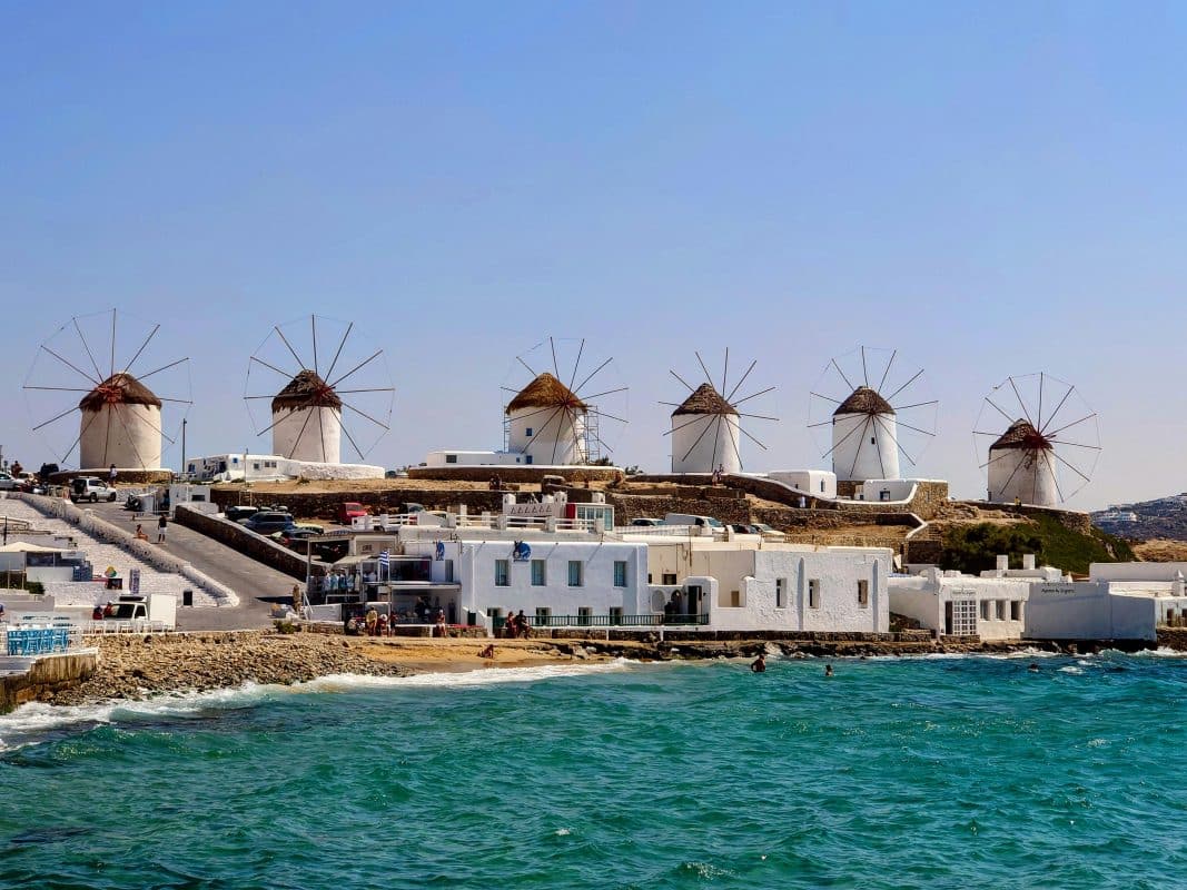 View of Mykonos windmills and coastline from the sea while arriving by ferry in the Greek islands
