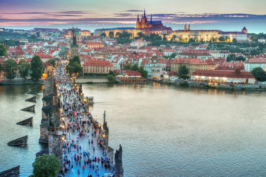 Crowds walking across Charles Bridge in Prague Czech Republic at sunset