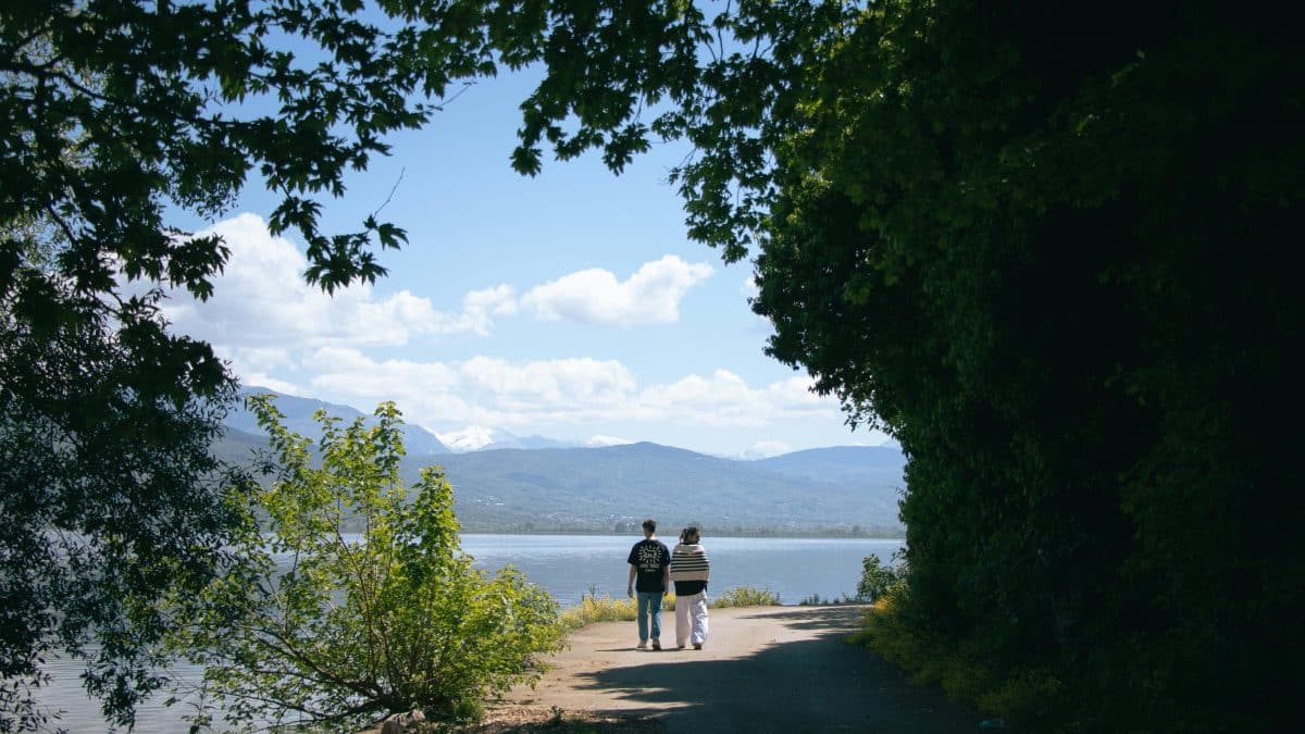 Couple walking along the lakeside path of Lake Pamvotida in Ioannina, Epirus Greece with mountains in the background