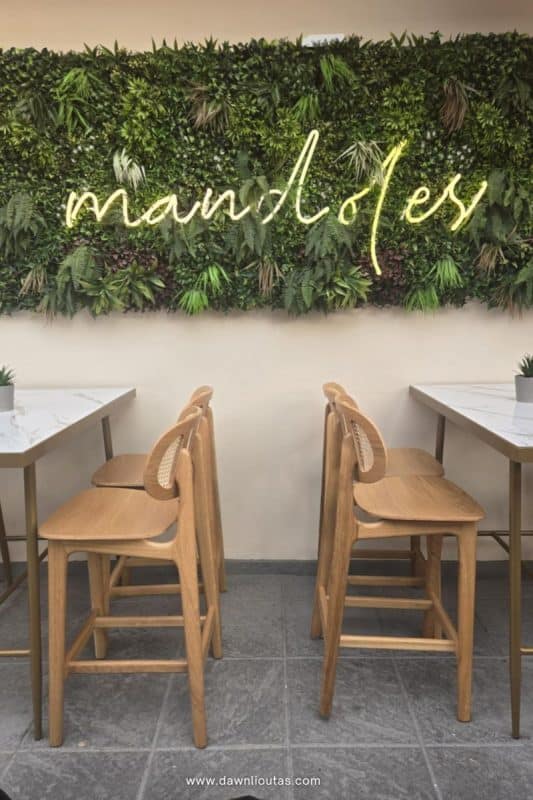 Patio of Mandoles restaurant in Parga Greece with greenery wall and seating