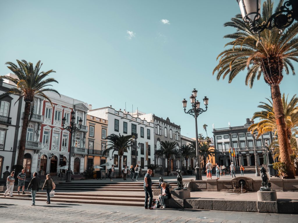 People walking through a historic plaza with palm trees and colonial buildings in Santa Cruz de Tenerife Canary Islands