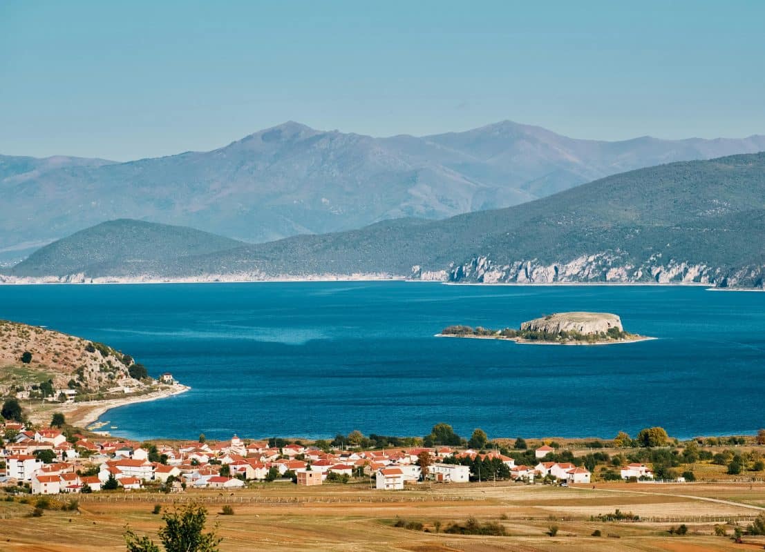 Scenic view of Lake Prespa in Albania with turquoise water, mountains, and a small lakeside village