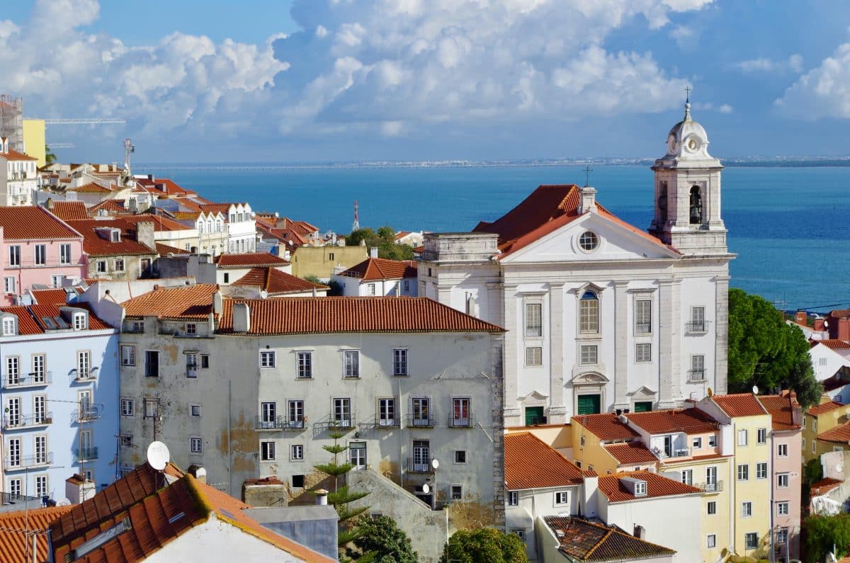 Colorful rooftops and historic church in Alfama Lisbon overlooking the Tagus River in Portugal