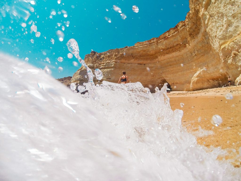Wave splashing on a sandy beach below Algarve Portugal cliffs