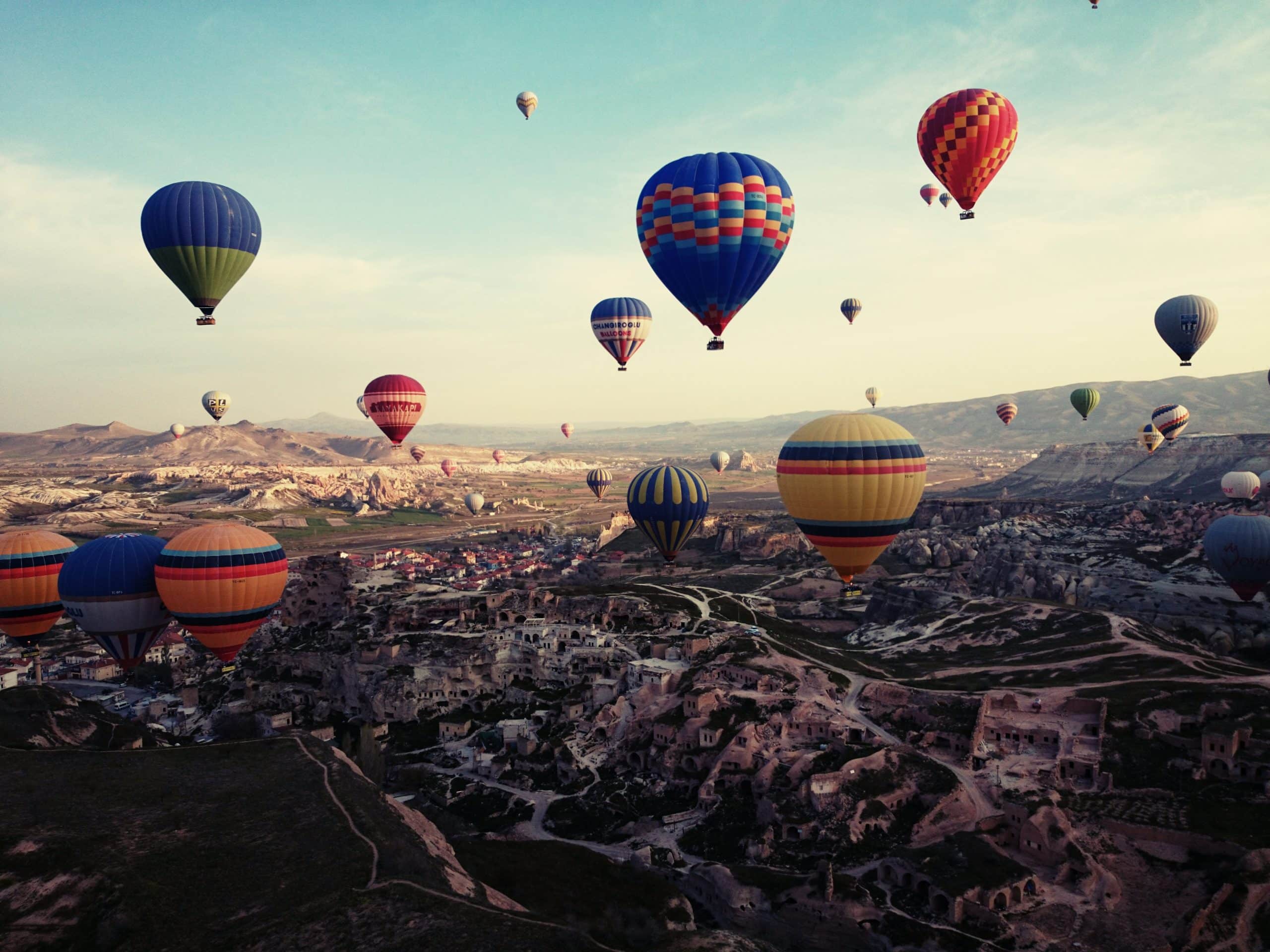 Hot air balloons flying over Cappadocia at sunrise with fairy chimneys landscape