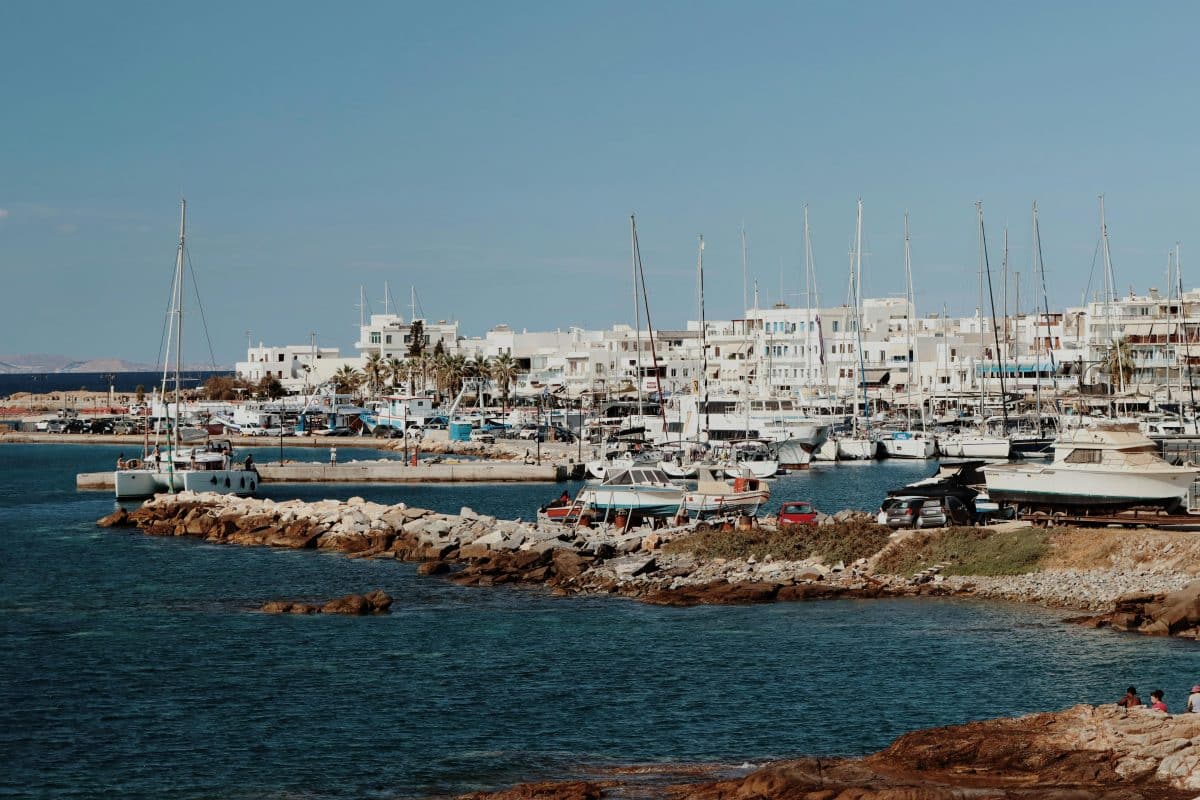 Boats and sailboats in Naxos harbor with turquoise water in Naxos, Greece