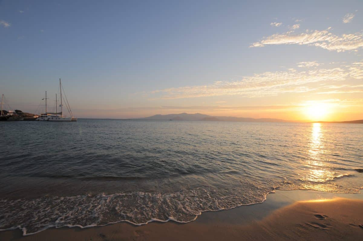Sunset over the Aegean Sea on a beach in Naxos, Greece with golden light and calm waves