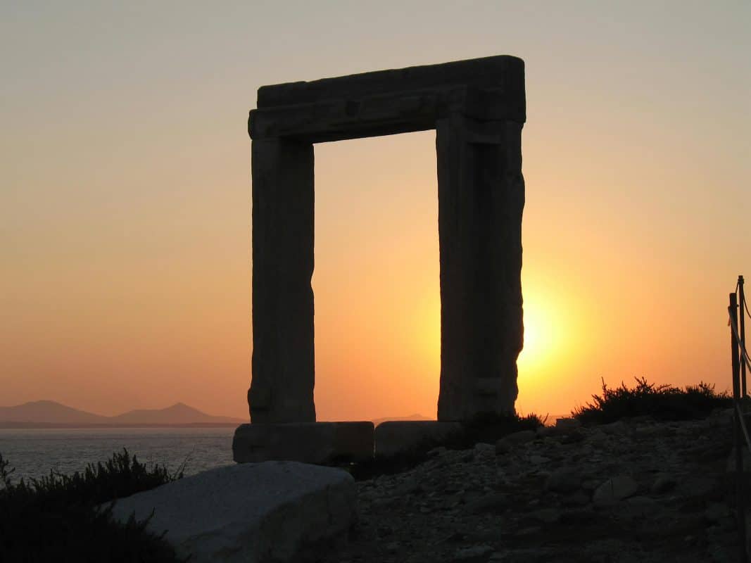 Portara in Naxos, Greece at sunset with the sun setting behind the ancient marble gate