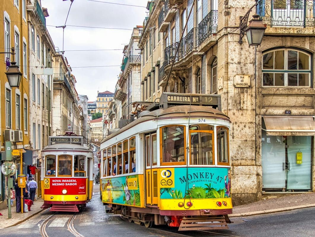 yellow tram 28 in lisbon passing through narrow alfama street