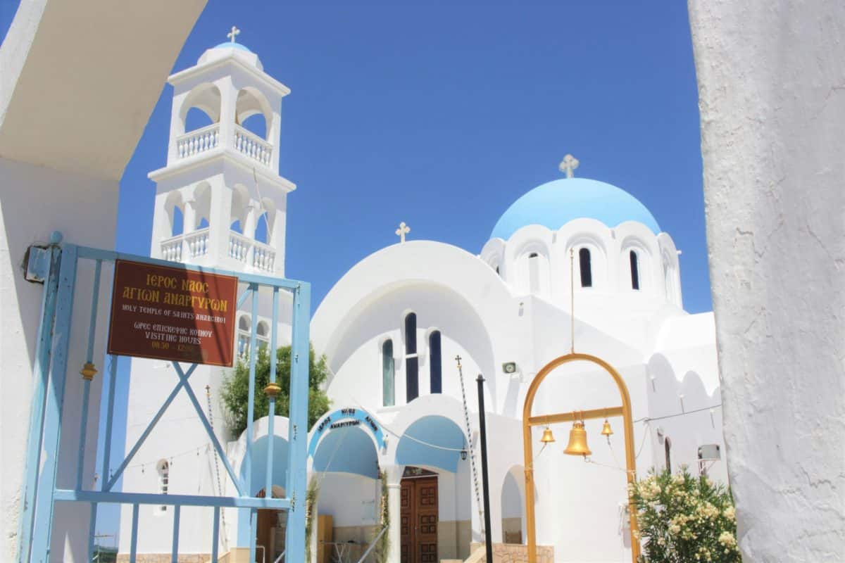 White church with blue dome in Skala Agkistri Greece under clear blue sky