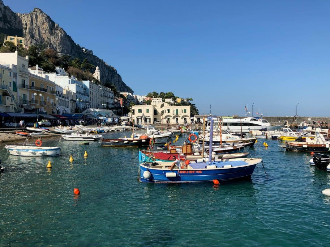 Capri Italy marina with colorful boats, turquoise water, and coastal buildings