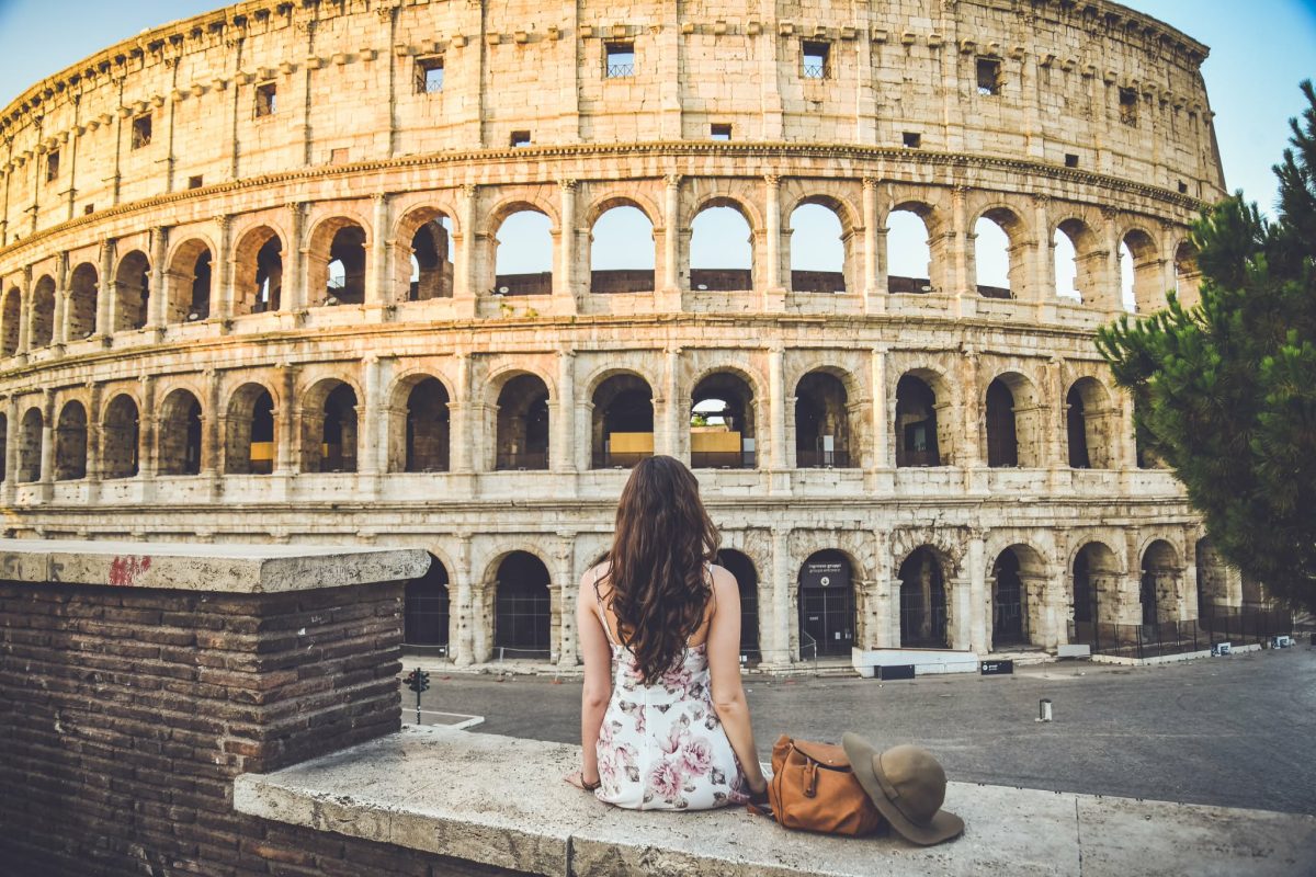 Woman sitting in front of the Colosseum in Rome Italy at sunrise with empty streets