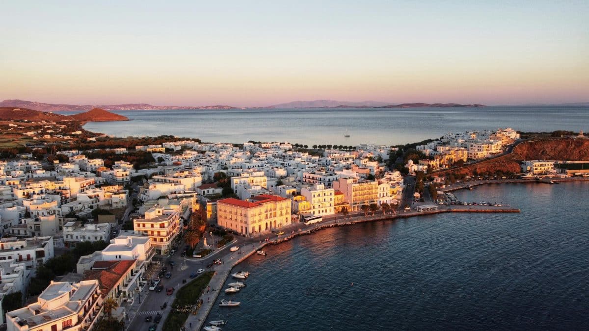 Aerial view of Tinos Town harbor at sunset with waterfront and Cycladic buildings