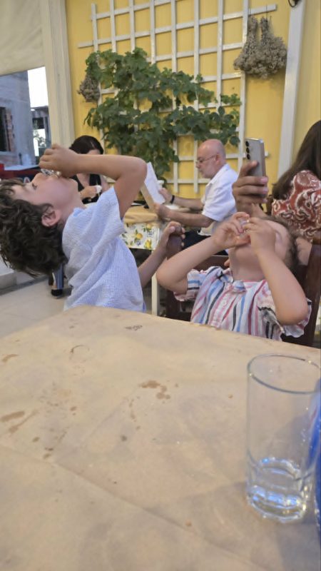 Kids enjoying a complimentary dessert drink at Toxotis restaurant in Agkistri Greece