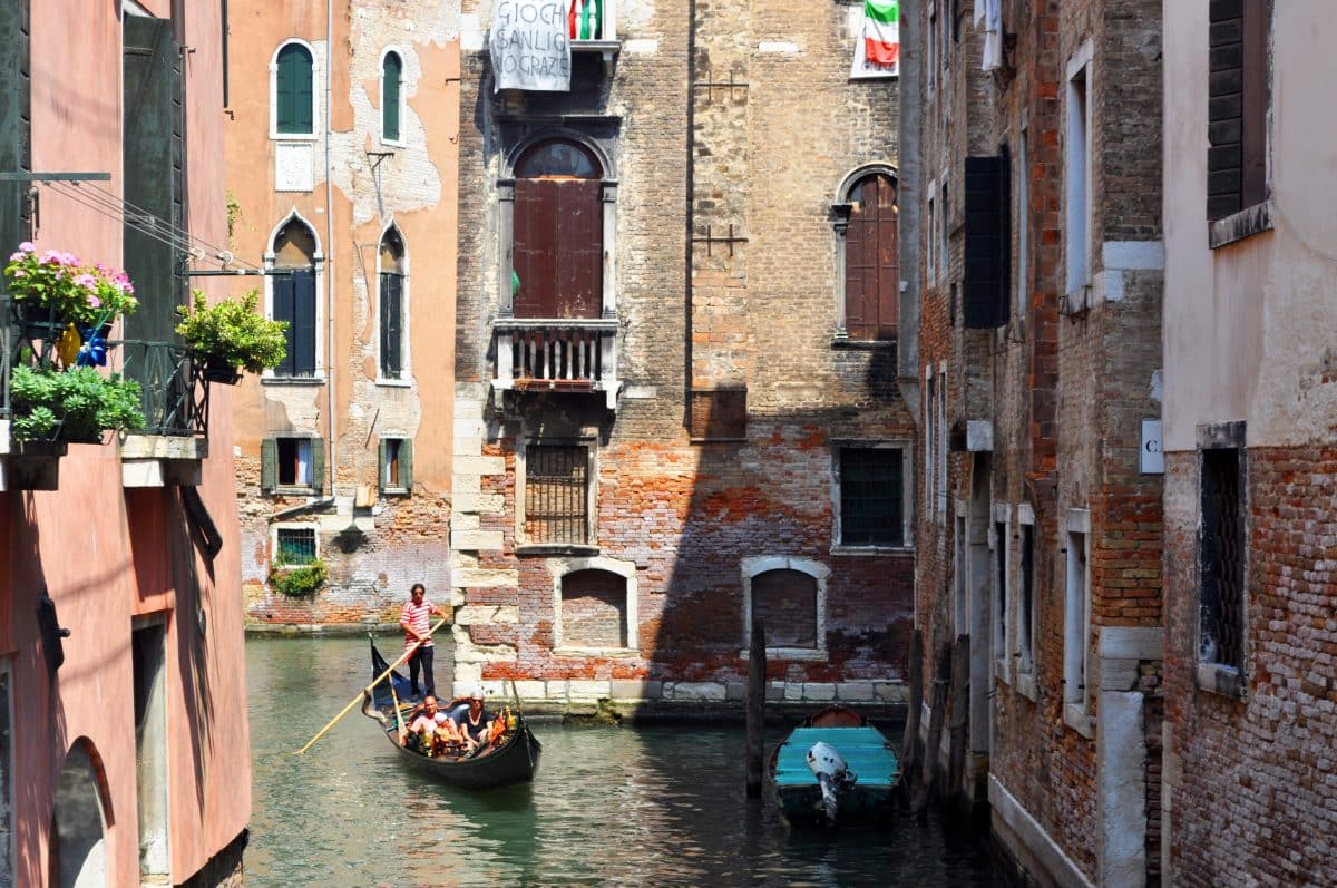 gondola ride through narrow canal in Venice Italy with historic buildings