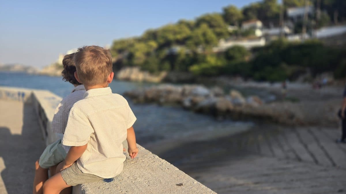 Two children sitting beside the waterfront on Agistri Island, Greece