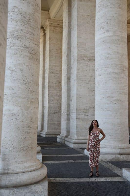 Woman standing between the large columns at St. Peter’s Basilica in Vatican City, Rome