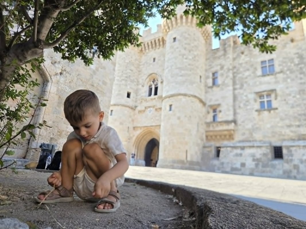 Toddler exploring outside the Palace of the Grand Master in Rhodes Old Town, one of the best Greek islands to visit without a car for families.