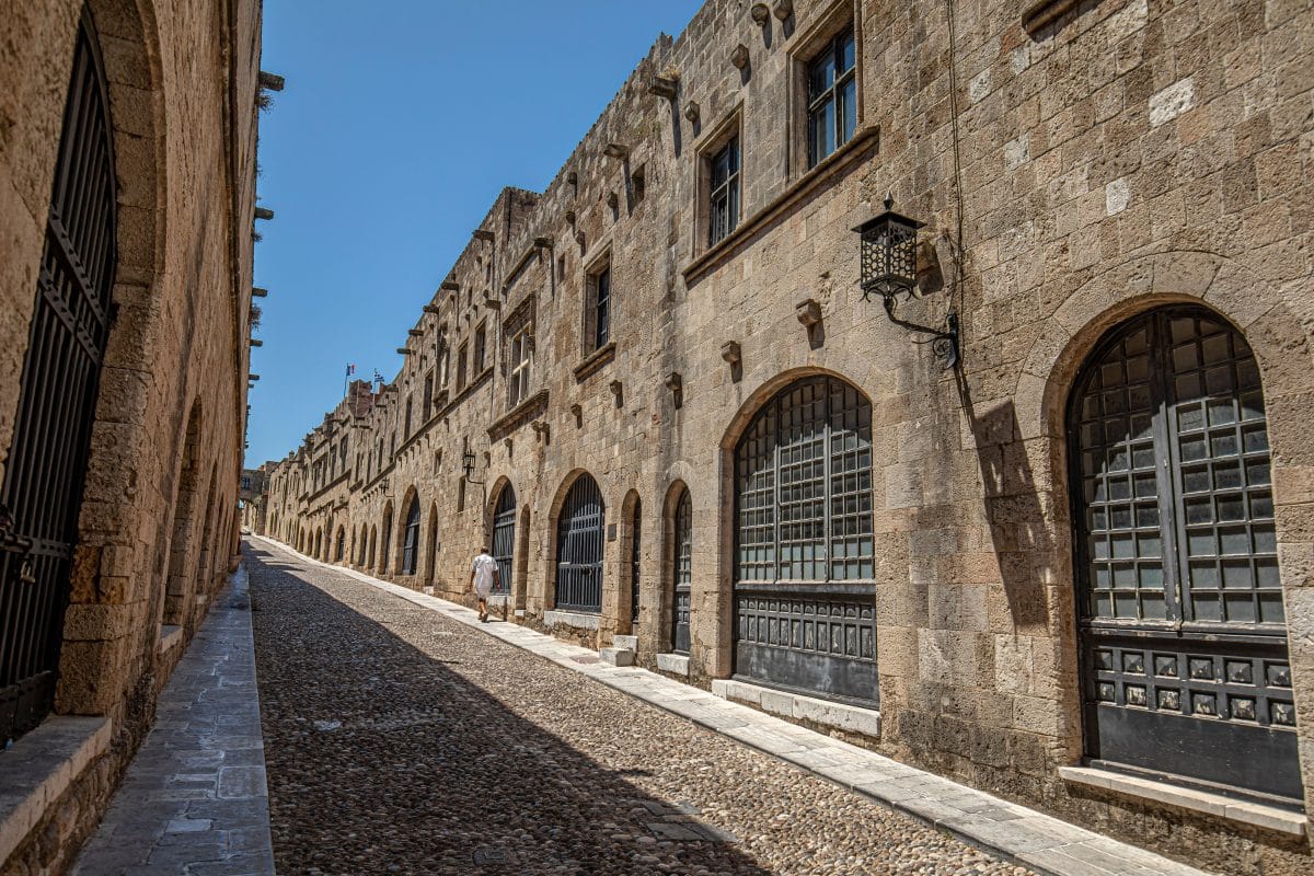 Historic cobblestone street lined with medieval stone buildings in Rhodes Old Town, Greece.