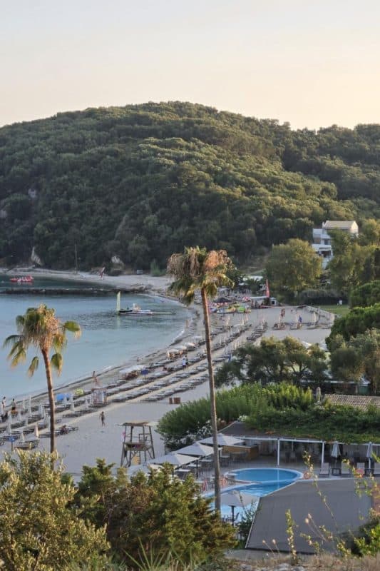 Overlooking Valtos Beach in Parga, Greece, with rows of sunbeds, clear water, and green hills surrounding the bay.