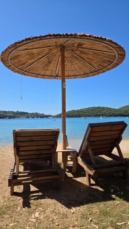 Sun loungers under a straw umbrella at Zeri Beach in Syvota, Greece