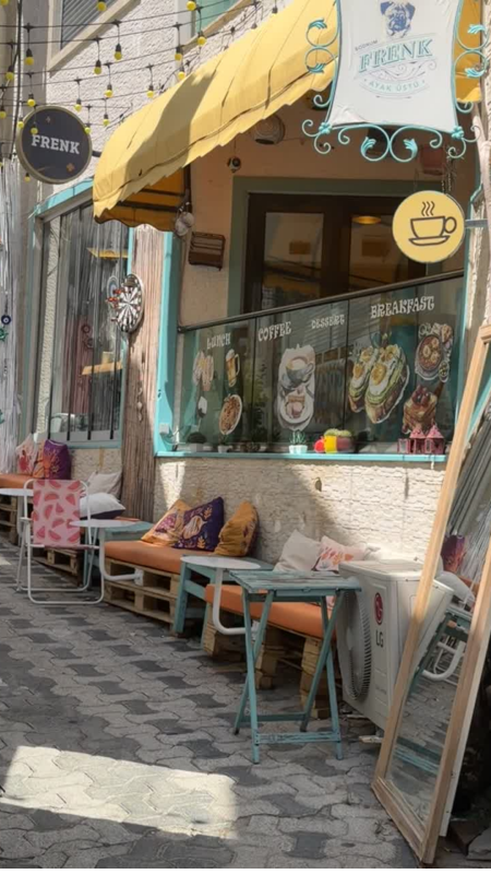 Exterior of Frenk Cafe in Bodrum, Turkey, with its yellow awning, outdoor seating and café sign.