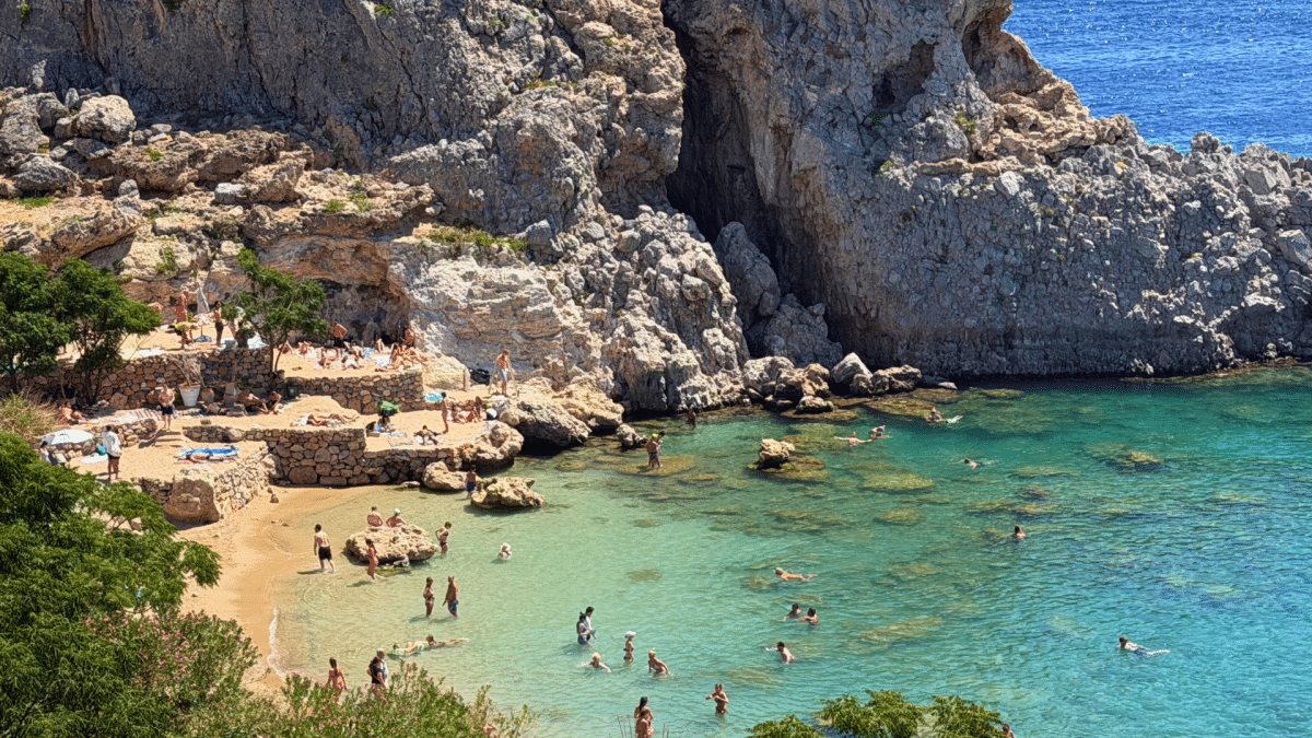 Mikros Gialos Beach in Lindos, Rhodes, Greece, with turquoise water and rocky cliffs